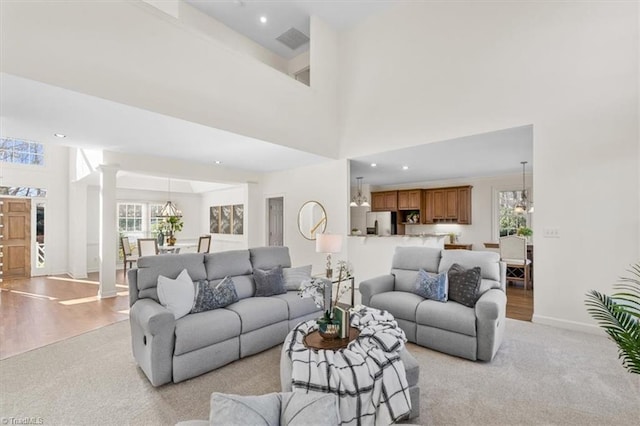 living room featuring a high ceiling, light colored carpet, and ornate columns