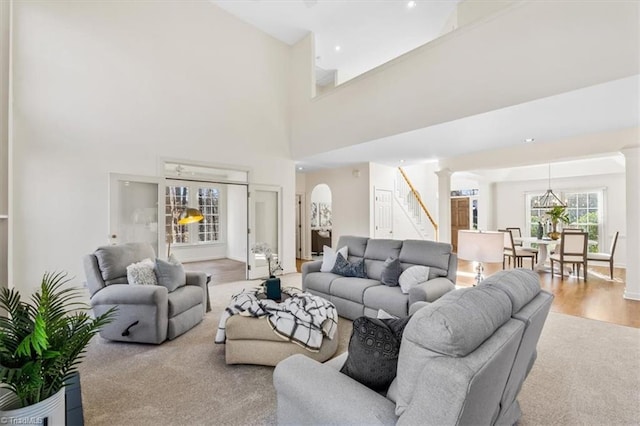 living room featuring decorative columns, a towering ceiling, and hardwood / wood-style flooring