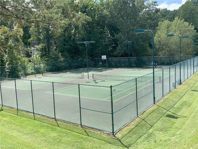 view of tennis court featuring a lawn