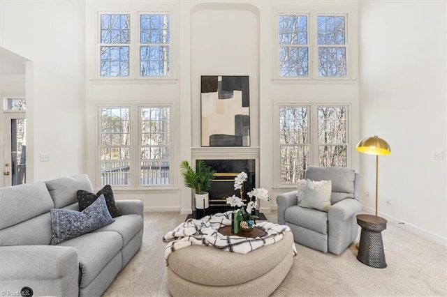 living room featuring a premium fireplace, carpet floors, and a high ceiling