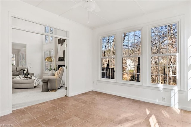 sunroom / solarium featuring ceiling fan and a fireplace