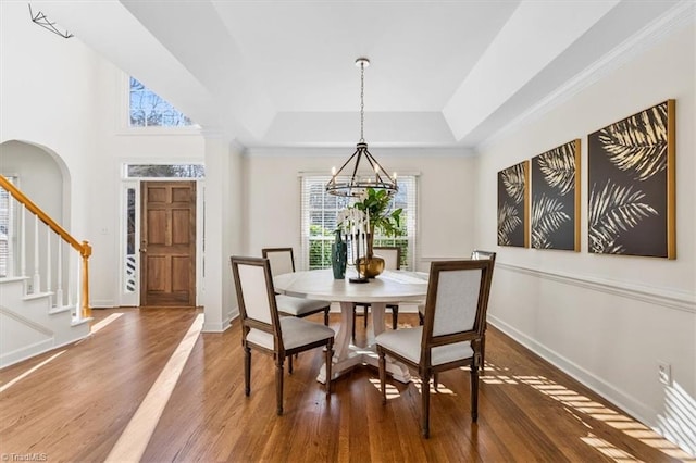 dining area with a raised ceiling, a chandelier, and hardwood / wood-style flooring