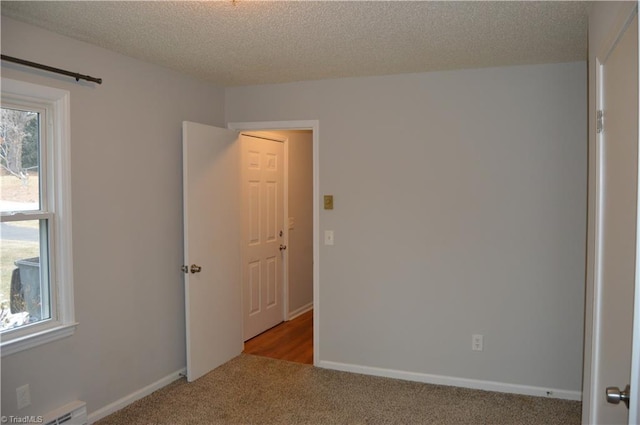 empty room featuring a baseboard radiator, a textured ceiling, baseboards, and carpet flooring