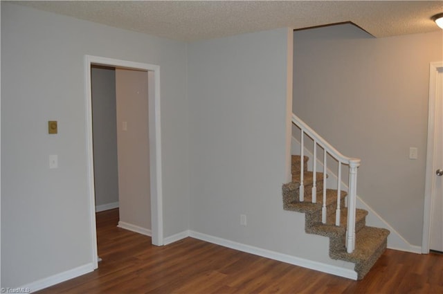 stairway featuring a textured ceiling, baseboards, and wood finished floors