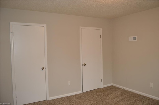 carpeted empty room featuring a textured ceiling