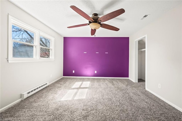 empty room with carpet, baseboards, visible vents, and baseboard heating