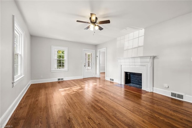 unfurnished living room with hardwood / wood-style flooring, a brick fireplace, and ceiling fan