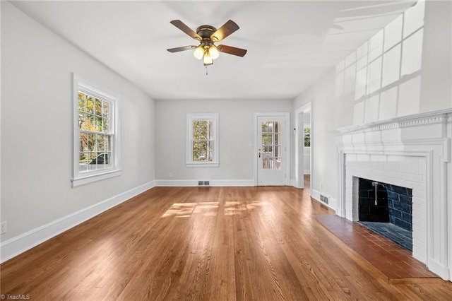 unfurnished living room with hardwood / wood-style floors, ceiling fan, and a brick fireplace