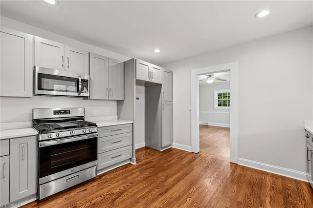 kitchen featuring ceiling fan, gray cabinets, wood-type flooring, and appliances with stainless steel finishes