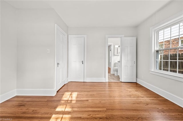 unfurnished bedroom with light hardwood / wood-style floors and ensuite bath