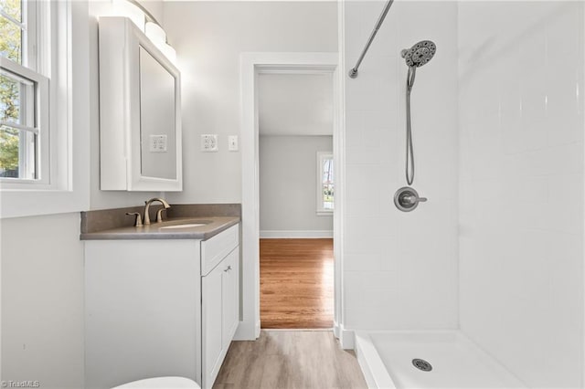 bathroom with a tile shower, vanity, and hardwood / wood-style flooring