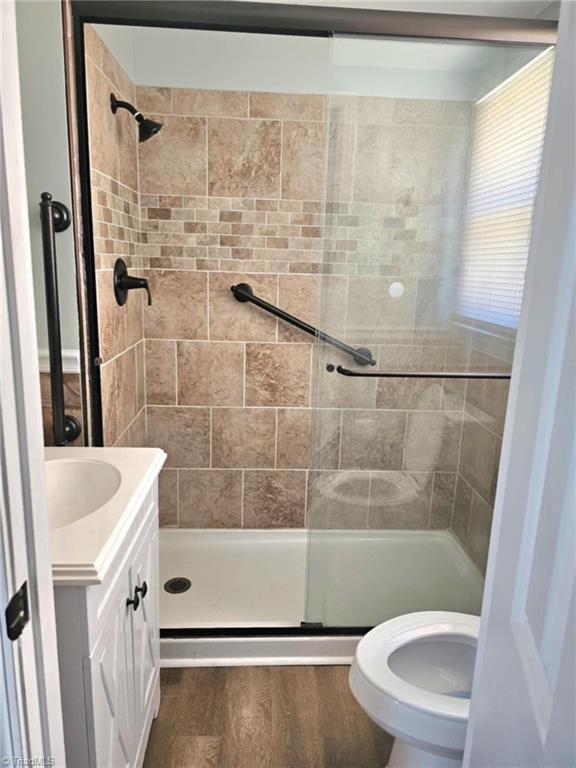 full bath with toilet, a shower stall, wood finished floors, and vanity