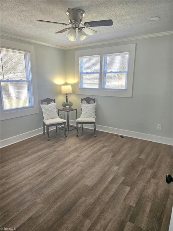 sitting room with ornamental molding, visible vents, and dark wood finished floors