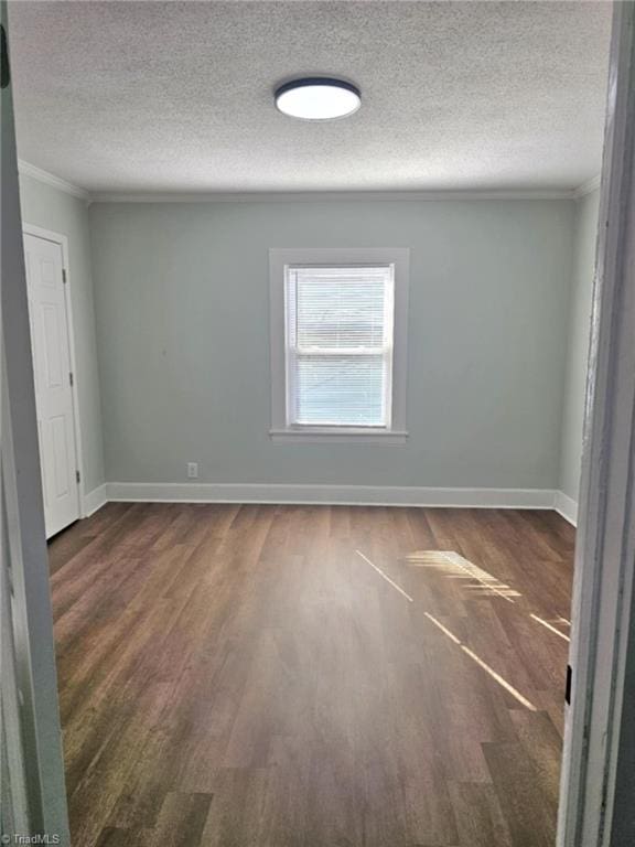 unfurnished room featuring crown molding, a textured ceiling, baseboards, and wood finished floors