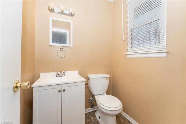 bathroom with toilet, vanity, and baseboards