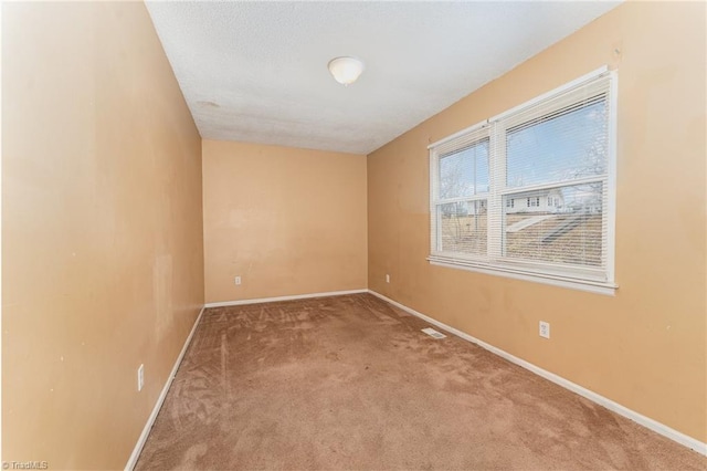 carpeted spare room with visible vents, baseboards, and a textured ceiling