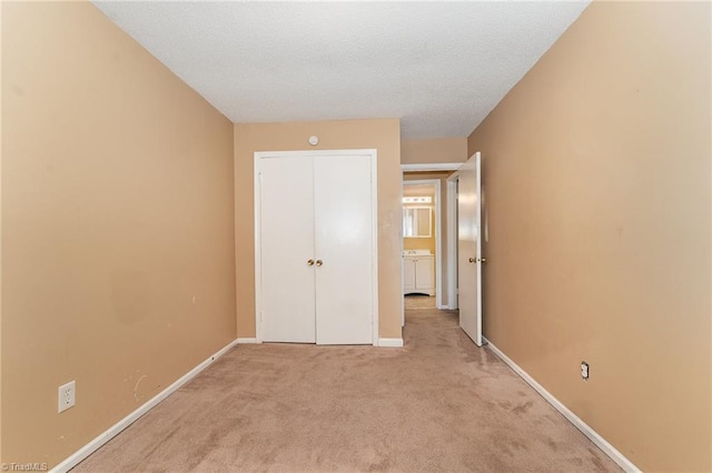 unfurnished bedroom featuring light colored carpet, baseboards, a closet, and a textured ceiling