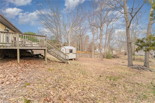 view of yard featuring fence, a shed, a wooden deck, stairs, and an outdoor structure