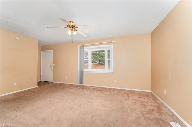 carpeted spare room featuring baseboards and a ceiling fan