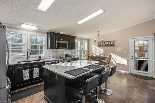 kitchen featuring a breakfast bar, sink, appliances with stainless steel finishes, a kitchen island, and light stone counters