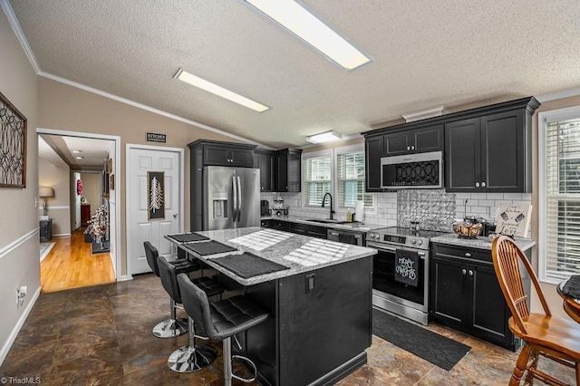 kitchen with a center island, lofted ceiling, a kitchen breakfast bar, sink, and stainless steel appliances