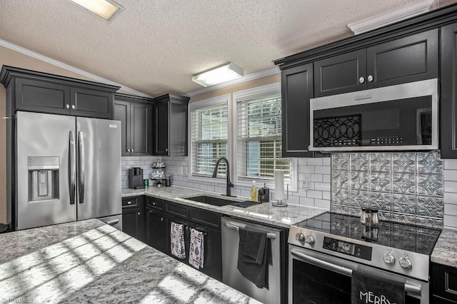 kitchen featuring sink, vaulted ceiling, a textured ceiling, decorative backsplash, and appliances with stainless steel finishes