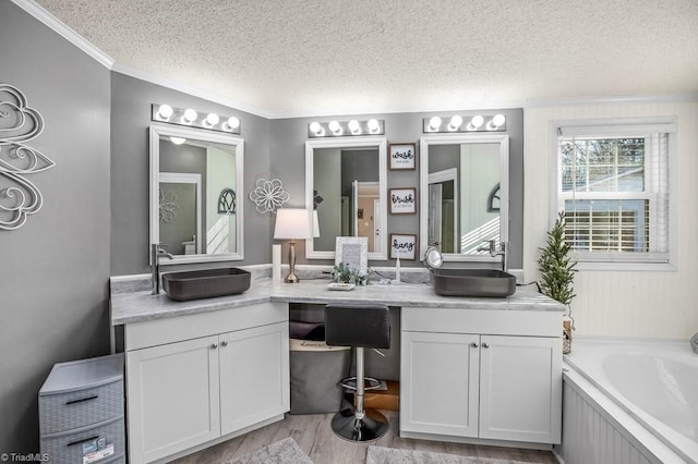 bathroom with vanity, a textured ceiling, hardwood / wood-style flooring, and a washtub