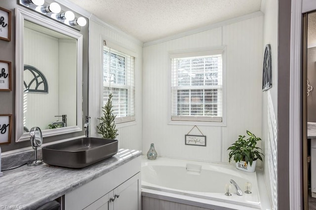 bathroom featuring a tub, vanity, a healthy amount of sunlight, and a textured ceiling