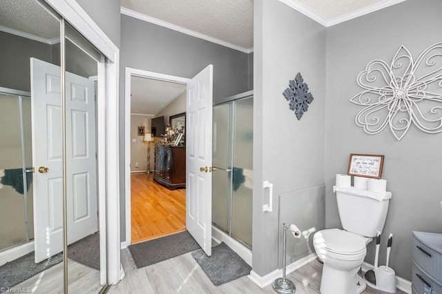 bathroom featuring toilet, an enclosed shower, wood-type flooring, and a textured ceiling