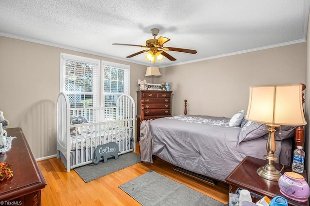 bedroom with hardwood / wood-style floors, a textured ceiling, ceiling fan, and ornamental molding