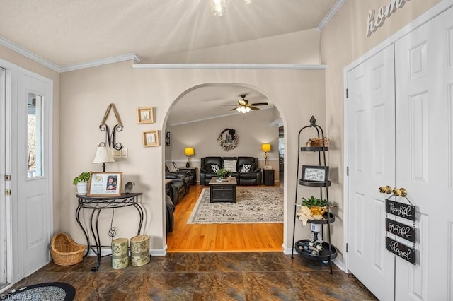 foyer entrance with ceiling fan, ornamental molding, and vaulted ceiling