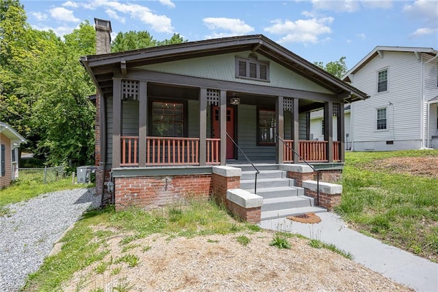 view of front of house featuring a porch, a chimney, and cooling unit