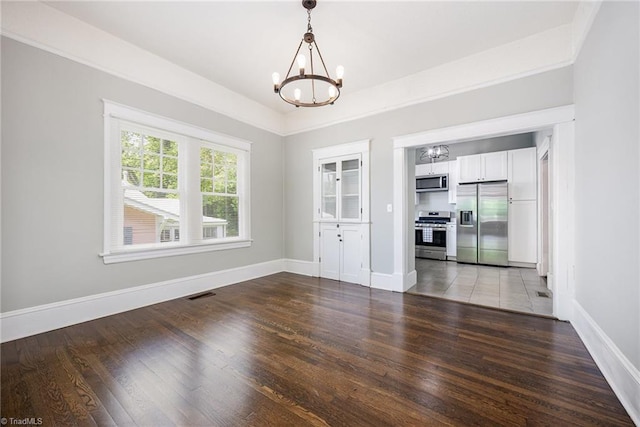 unfurnished dining area featuring a chandelier, wood finished floors, and baseboards