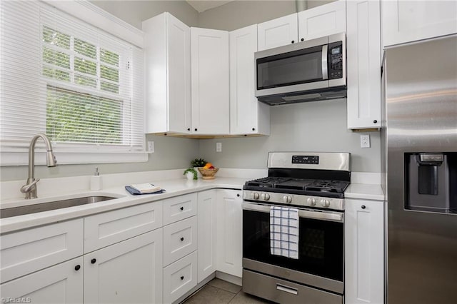 kitchen featuring stainless steel appliances, a sink, light countertops, and white cabinets