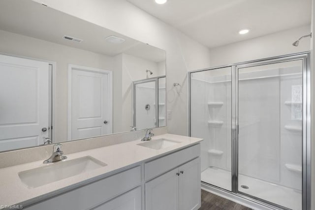 bathroom with hardwood / wood-style flooring, walk in shower, and vanity