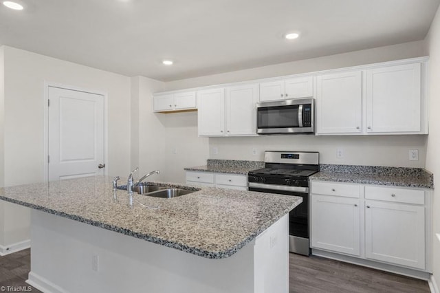 kitchen with stainless steel appliances, white cabinets, a kitchen island with sink, and sink