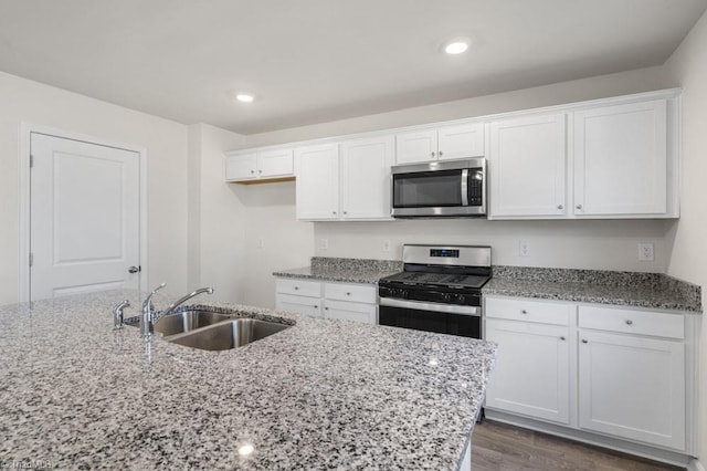 kitchen featuring light stone countertops, white cabinets, sink, dark hardwood / wood-style flooring, and appliances with stainless steel finishes