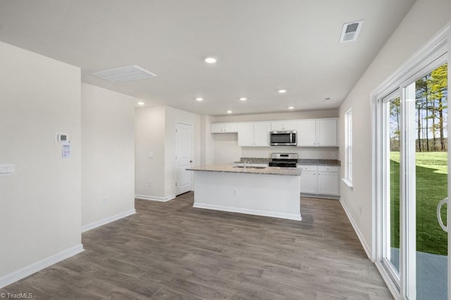 kitchen featuring an island with sink, light stone countertops, stainless steel appliances, hardwood / wood-style flooring, and white cabinetry