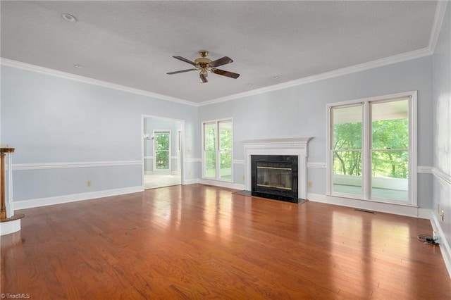 unfurnished living room with ceiling fan, visible vents, a glass covered fireplace, ornamental molding, and wood finished floors