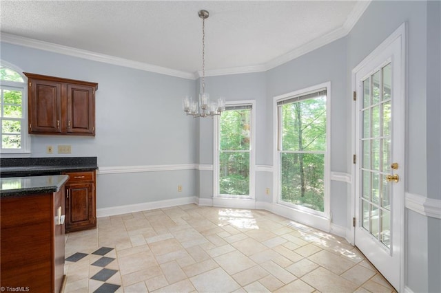 unfurnished dining area with ornamental molding, stone tile floors, a chandelier, and baseboards