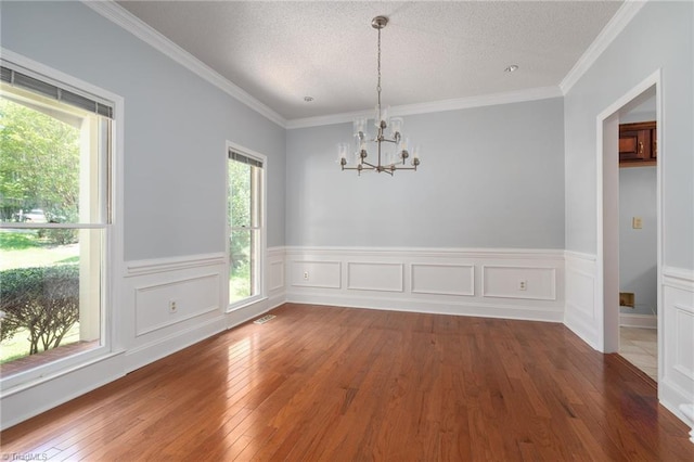 unfurnished dining area with a chandelier, wainscoting, a textured ceiling, and wood-type flooring