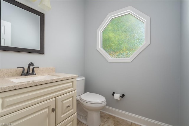 half bath featuring vanity, toilet, tile patterned flooring, and baseboards