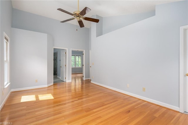 spare room featuring ceiling fan, high vaulted ceiling, light wood finished floors, and baseboards