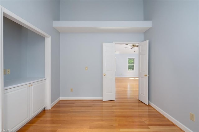 unfurnished room with a ceiling fan, baseboards, and light wood-type flooring