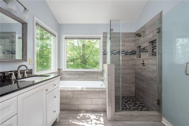 full bathroom with a stall shower, a bath, lofted ceiling, and vanity