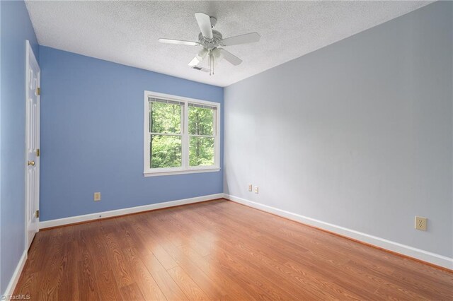 spare room featuring a textured ceiling, wood finished floors, and baseboards
