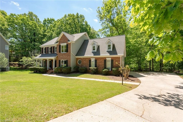 colonial inspired home with roof with shingles, concrete driveway, a front yard, and brick siding