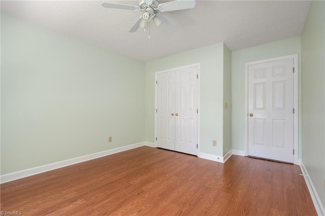 unfurnished bedroom featuring a closet, ceiling fan, wood finished floors, and baseboards