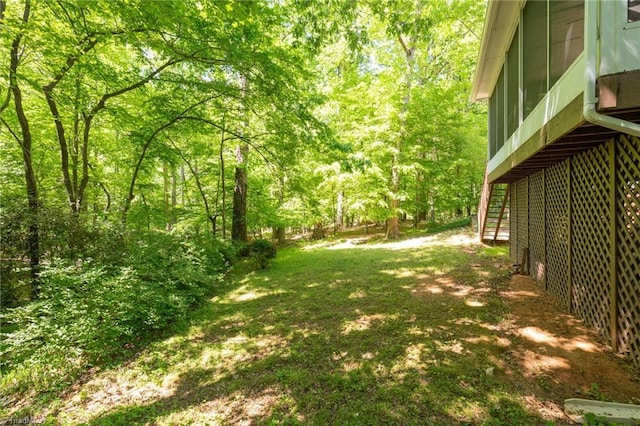 view of yard featuring a wooded view and stairs