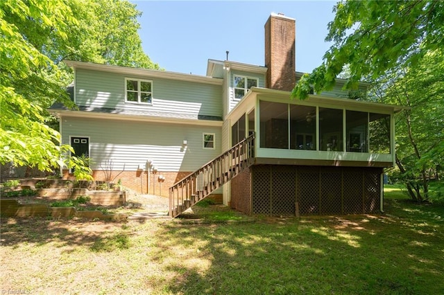 back of property featuring a sunroom, a lawn, stairway, and a chimney